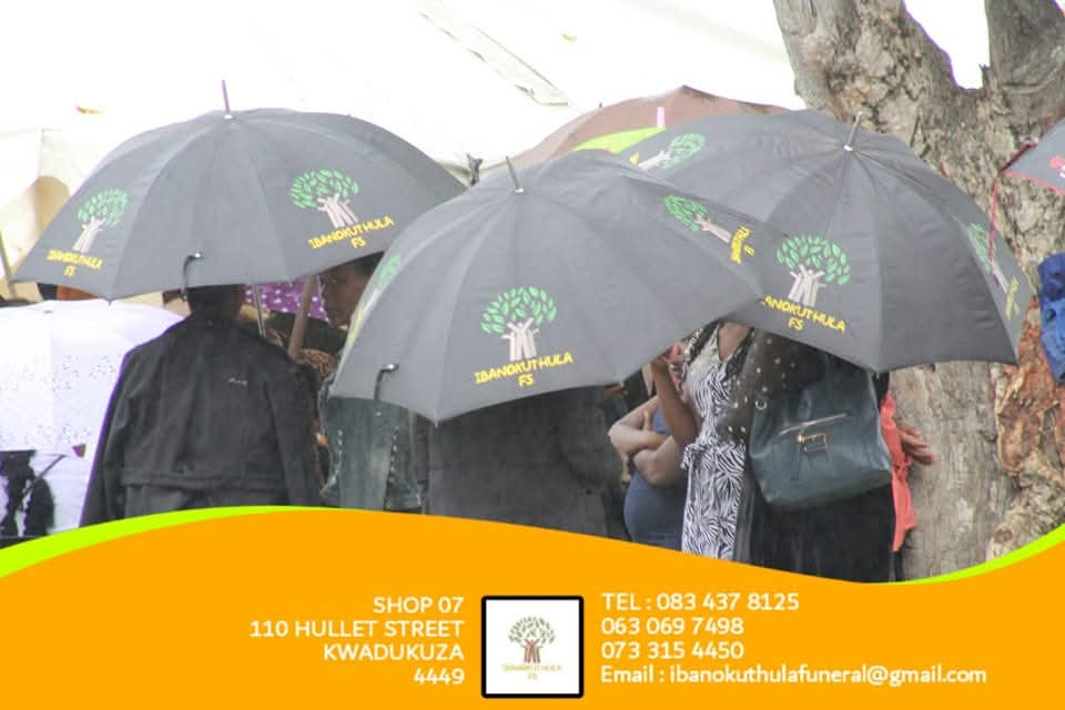 Community members sheltered by Ibanokuthula branded umbrellas